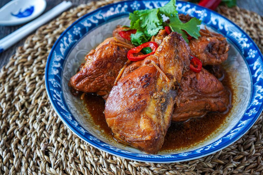 Gà Xào Gừng (Braised Chicken in Ginger) in a blue and gray bowl with red chili slices and cilantro.