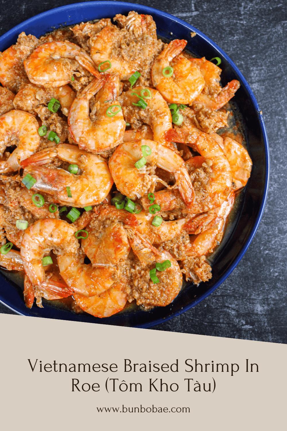 A plate of head-on shrimp next to some cloves of garlic, a shallot and some shrimp paste.