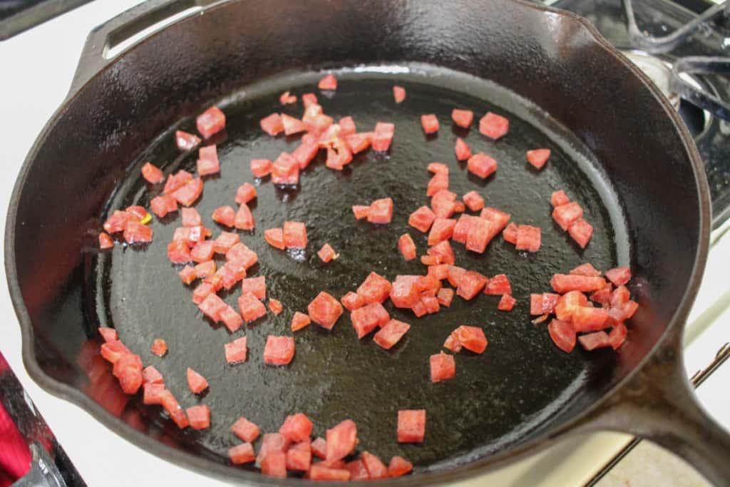Onions and carrots cooking down in a cast iron skillet